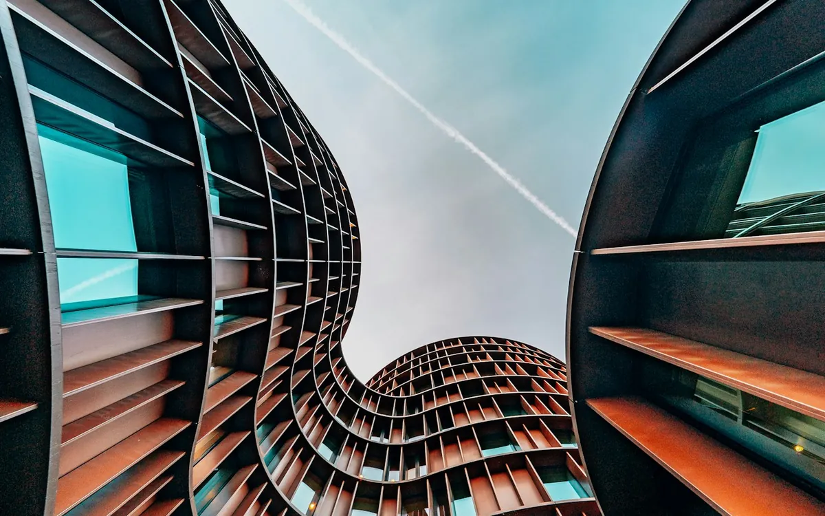 Curved glass and steel building rising against a sunlit sky