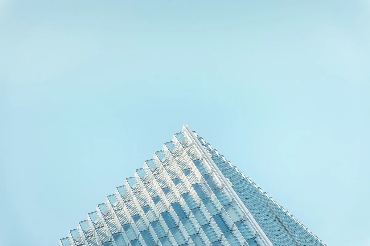 Pale blue sky above a sharply angled glass building corner