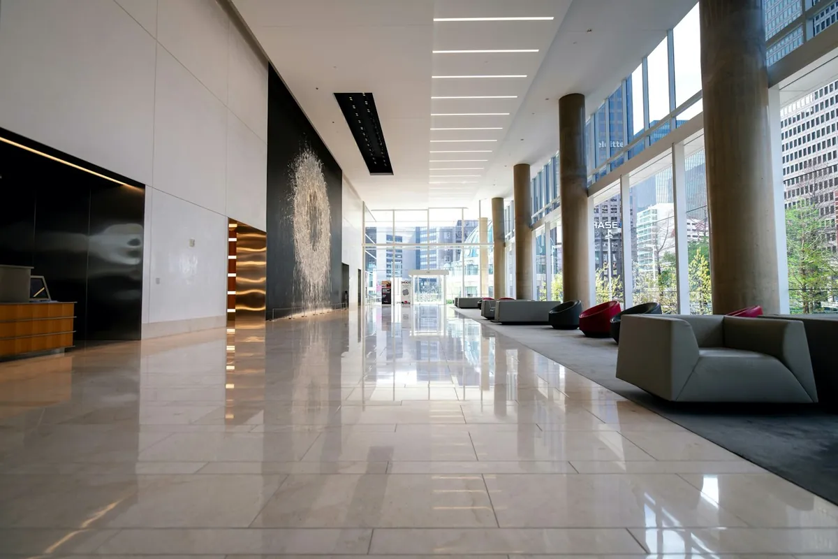Long marble lobby with wide windows and lounge seating in a modern building