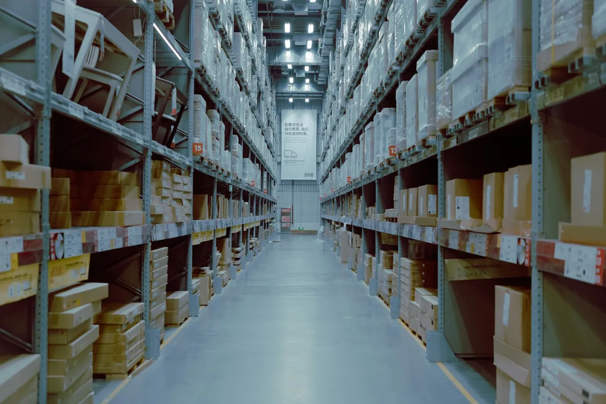 Tall warehouse aisle with racks of boxes under bright lights