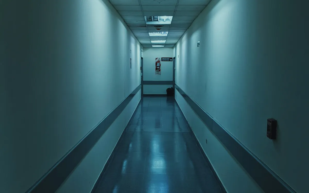 Long blue-tinted corridor with a lit ceiling in a dark building