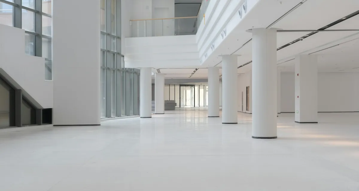 Bright white atrium hall with columns and large windows in a modern building
