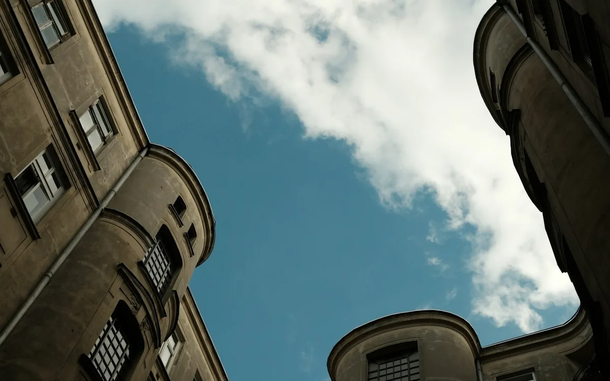 Looking up at a curved apartment block around a small patch of blue sky