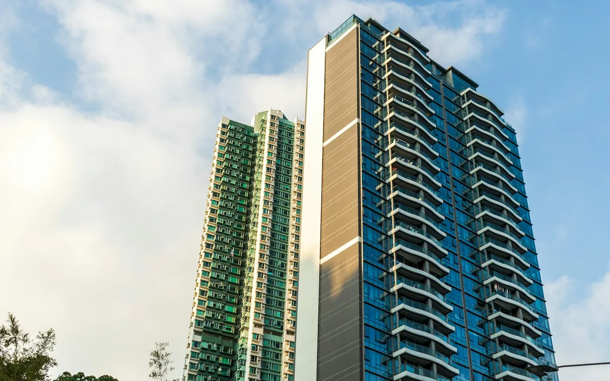 Modern blue high-rise apartment tower under a cloudy sky