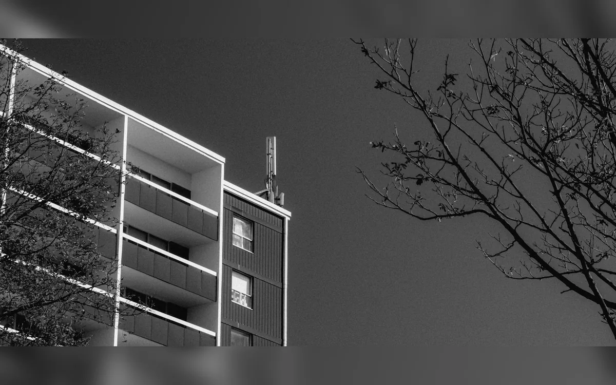 Black and white apartment building with balconies and bare trees
