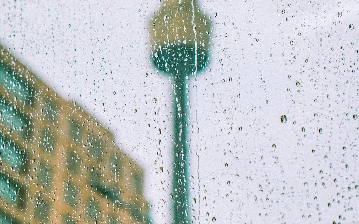 Rain-streaked window with a city tower in the background