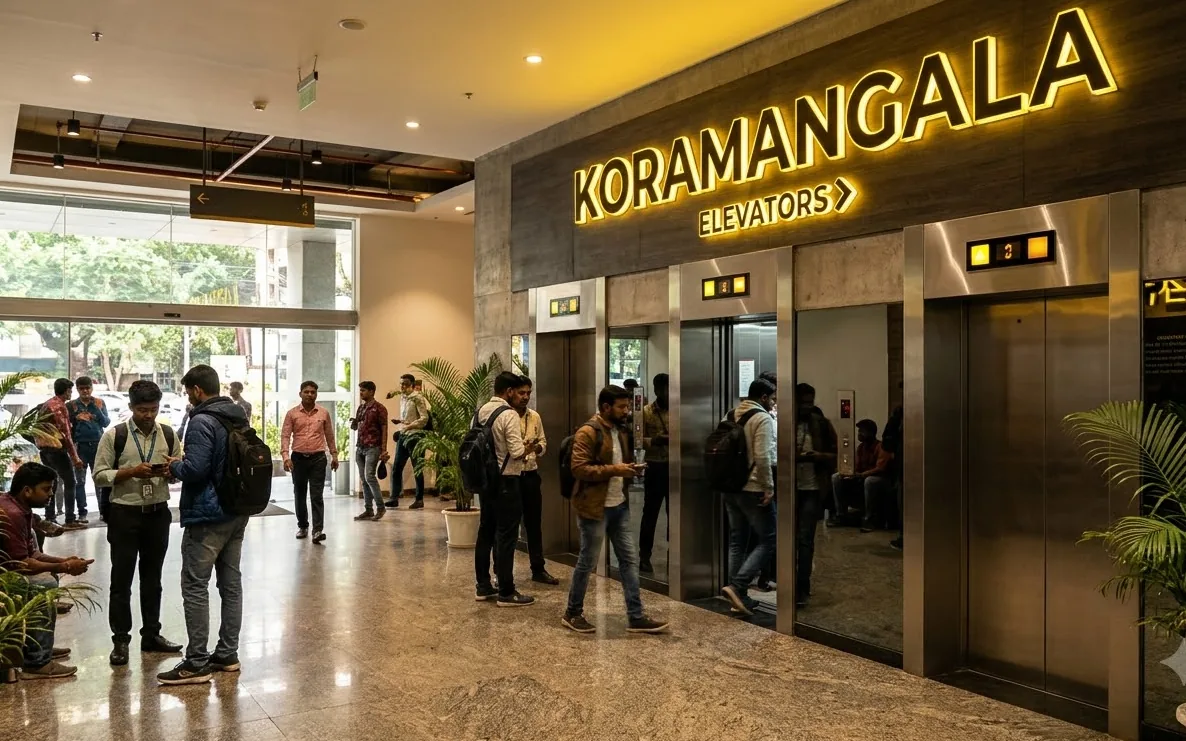Elevator beside a Koramangala street with cafes and builder floor buildings